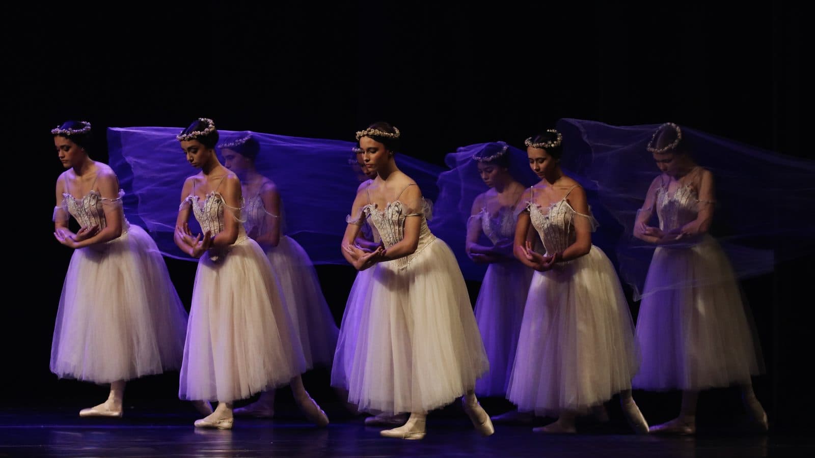 Corpo de baile com saias românticas brancas e véus lilases no palco do Theatro Carlos Gomes — MoviRio 2026
